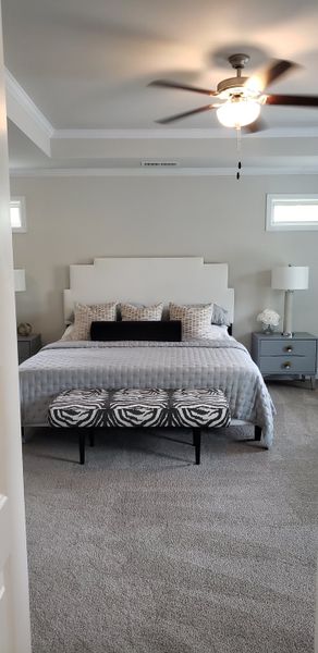 A chic bedroom featuring a plush bed with a light headboard, patterned bench, and neutral decor.