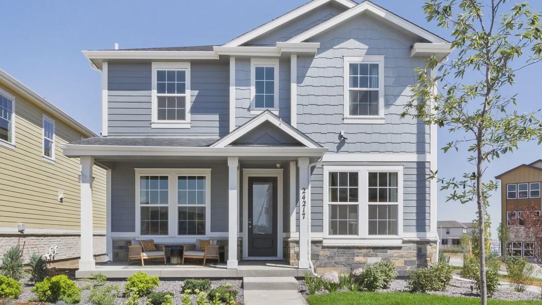 Elegant two-story home with a charming porch and striking stone facade in Windler community.