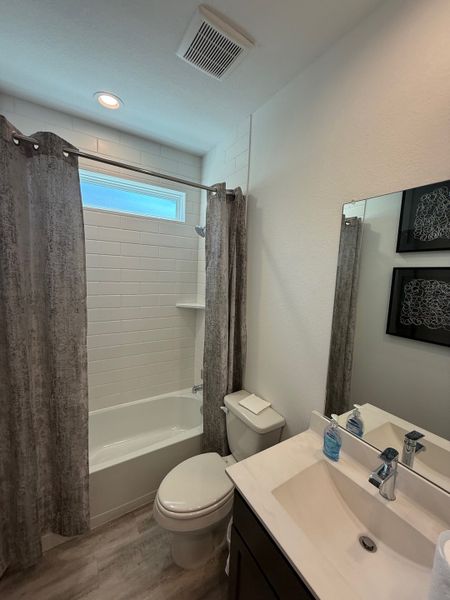 A modern bathroom featuring a sleek vanity, neutral tones, and elegant tiled shower with contemporary accents.