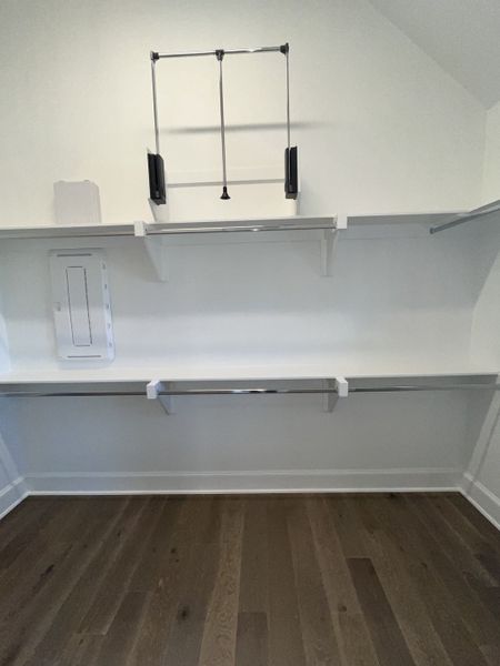 A spacious closet with hardwood floors, sleek white shelving, and modern hanging rods. A spacious closet with hardwood floors, sleek white shelving, and modern hanging rods.