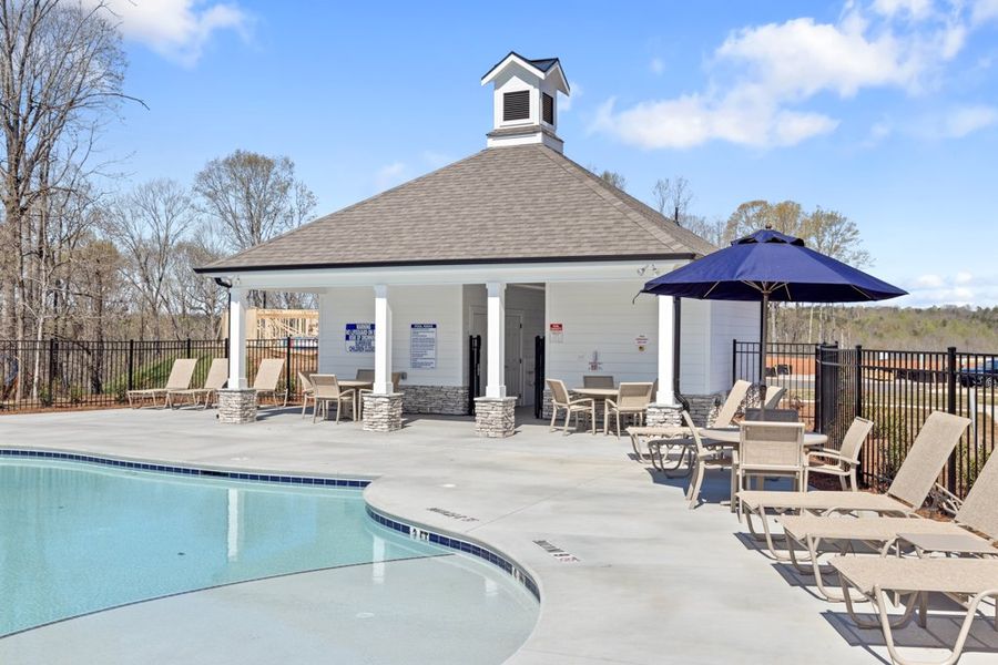 A pool with chairs and umbrellas by a house. A pool with chairs and umbrellas by a house.