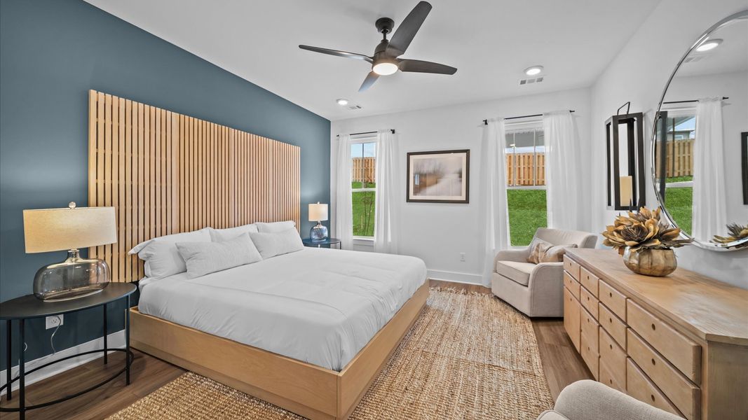 Primary suite with hardwood flooring, large windows, and ceiling fan at Aspen Ridge by DRB Homes in Lyman, SC Primary suite with hardwood flooring, large windows, and ceiling fan at Aspen Ridge by DRB Homes in Lyman, SC