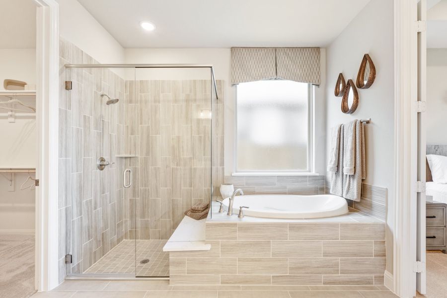 Master bathroom with glass walk-in shower, soaking tub, and neutral tile throughout Master bathroom with glass walk-in shower, soaking tub, and neutral tile throughout