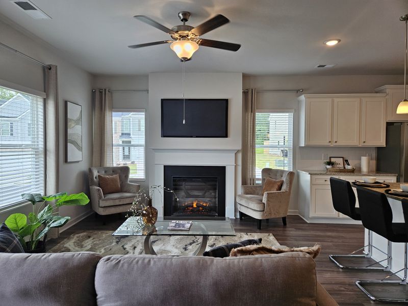 A cozy living room with a modern fireplace, comfy chairs, and a large TV, creating a serene atmosphere for relaxing.