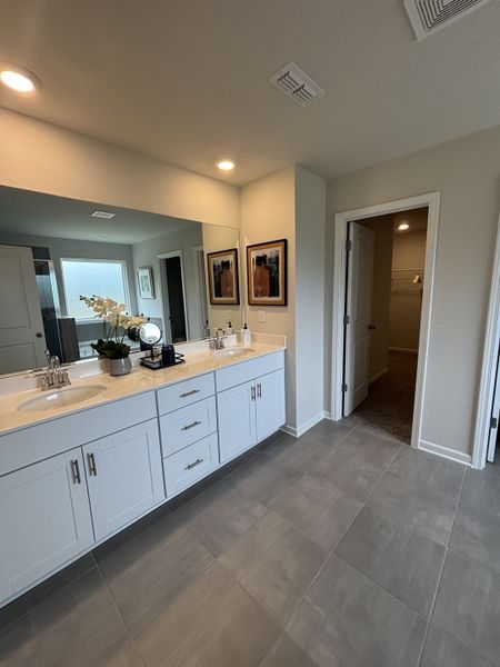 A spacious bathroom featuring a double vanity, sleek white cabinets, and elegant tile flooring.