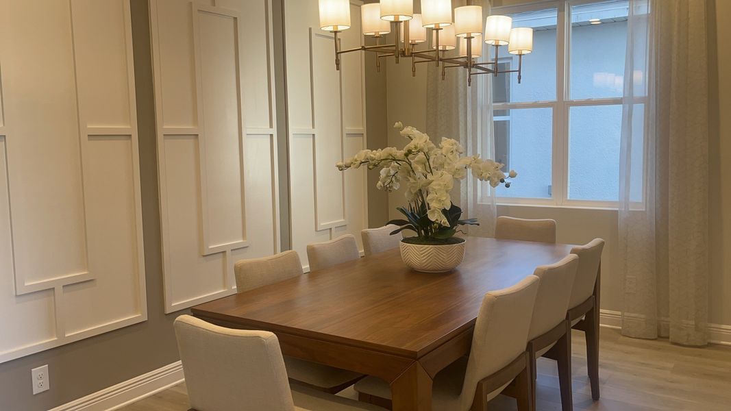 A sophisticated dining room featuring an elegant wooden table, soft beige chairs, and a chic chandelier. A sophisticated dining room featuring an elegant wooden table, soft beige chairs, and a chic chandelier.
