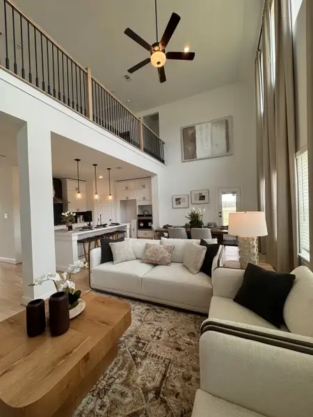 A spacious living area with high ceilings, modern decor, a cozy seating arrangement, and an elegant open kitchen. A spacious living area with high ceilings, modern decor, a cozy seating arrangement, and an elegant open kitchen.