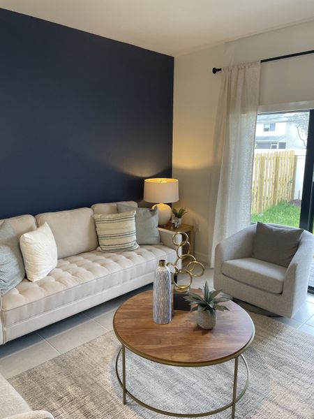 A cozy living room featuring a beige sofa, chic armchair, and a wooden coffee table with elegant decor.