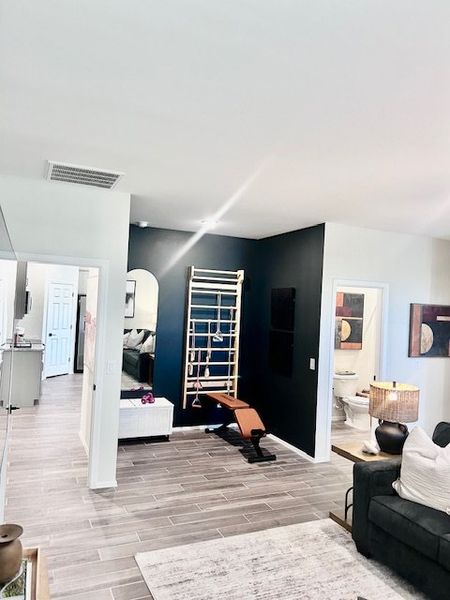 A modern living area with sleek tile flooring, a cozy gray sofa, and contemporary black accent wall.