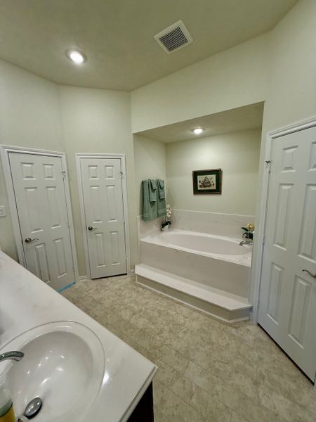 A spacious bathroom with a step-up bathtub, dual doors, and elegant lighting.