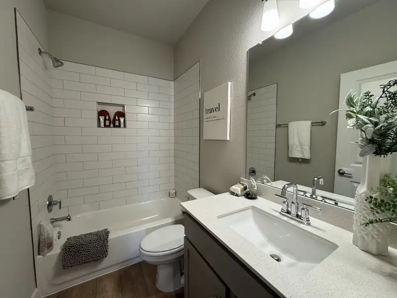 A modern bathroom featuring a sleek vanity, stylish lighting, and a tiled shower with niche.