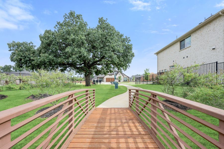 Wooden footbridge leading to a community walking path with a large oak tree and homes in the background Wooden footbridge leading to a community walking path with a large oak tree and homes in the background
