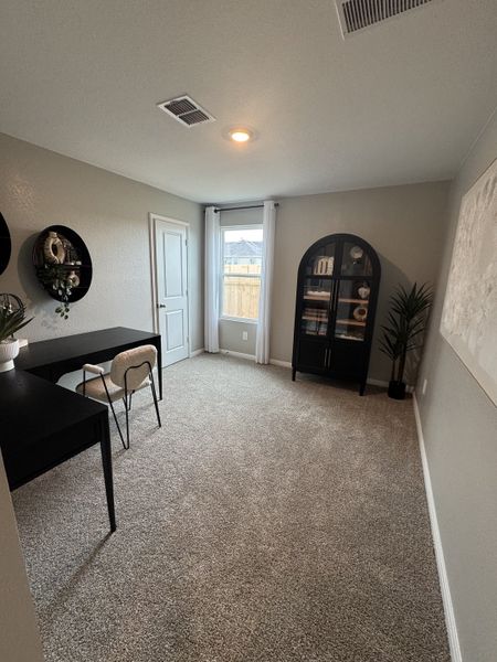 A cozy home office with plush carpet, a sleek black desk, and modern decor elements including wall shelves and a glass cabinet. A cozy home office with plush carpet, a sleek black desk, and modern decor elements including wall shelves and a glass cabinet.