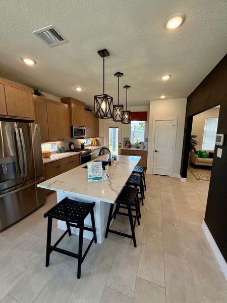 A modern kitchen featuring a sleek island, pendant lights, and stainless steel appliances with ample natural light. A modern kitchen featuring a sleek island, pendant lights, and stainless steel appliances with ample natural light.