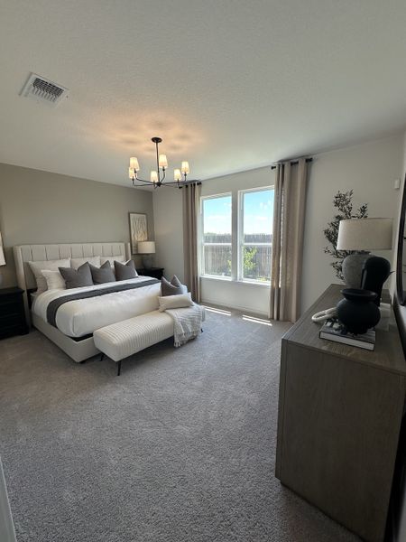 A cozy bedroom featuring plush carpeting, a modern bed with elegant bedding, and abundant natural light from large windows.