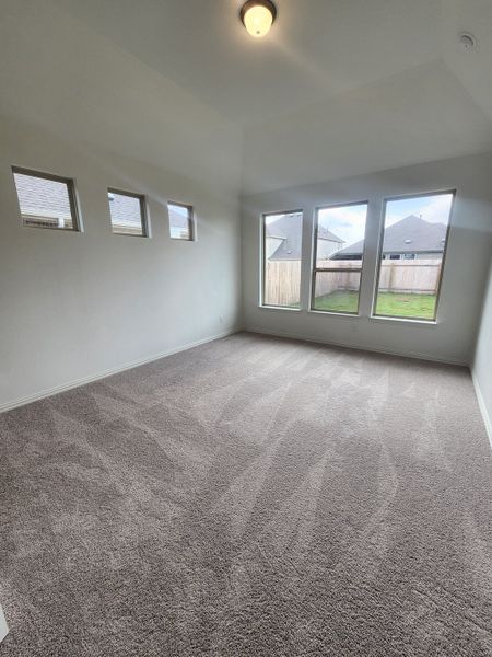 A bright room with large windows, gray carpet, and recessed lighting providing a spacious, airy feel. A bright room with large windows, gray carpet, and recessed lighting providing a spacious, airy feel.