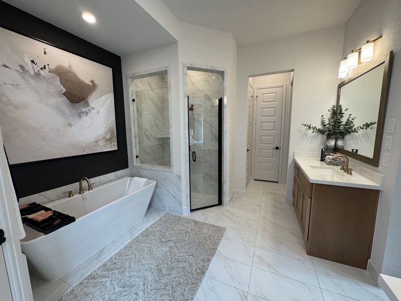 Elegant bathroom featuring a soaking tub, abstract art, glass shower, and a sleek vanity with stylish lighting.