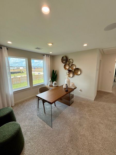 A cozy office with soft carpeting, modern decor, and a large window letting in natural light.