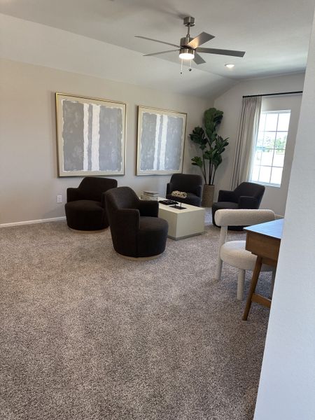 A cozy living area with plush chairs, modern art, and a chic ceiling fan, perfect for relaxation and gathering. A cozy living area with plush chairs, modern art, and a chic ceiling fan, perfect for relaxation and gathering.