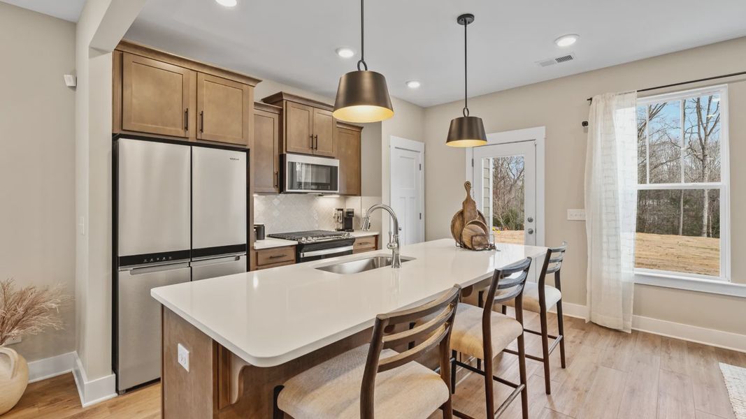 Spacious, cozy, modern kitchen with wooden cabinetry and large windows at Hickory Heights by DRB Homes