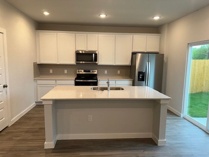A modern kitchen with sleek white cabinetry, stainless steel appliances, and a central island illuminated by recessed lighting. A modern kitchen with sleek white cabinetry, stainless steel appliances, and a central island illuminated by recessed lighting.
