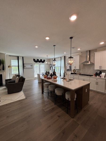 A contemporary open-concept kitchen with a large island, modern lighting, and cozy living area.