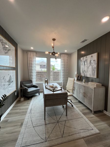 A modern office with sleek furniture, a stylish desk, patterned rug, and contemporary lighting.