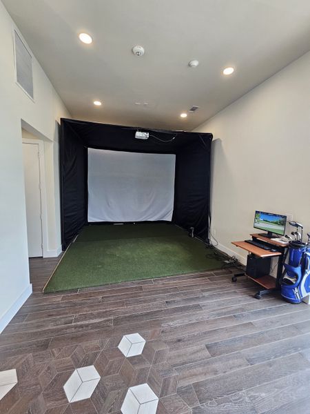A modern golf simulator room with sleek wood flooring and cozy lighting for ultimate indoor practice.