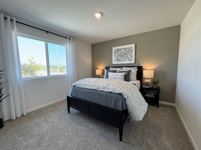 A cozy bedroom with a plush carpet, dark bed frame, and soft lighting, featuring a large window with a bright view. A cozy bedroom with a plush carpet, dark bed frame, and soft lighting, featuring a large window with a bright view.