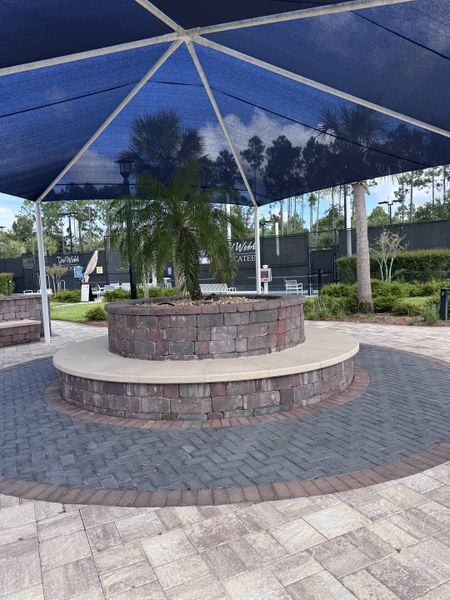 A charming stone patio with a shaded seating area in Del Webb Nocatee by Del Webb (Ponte Vedra, FL).