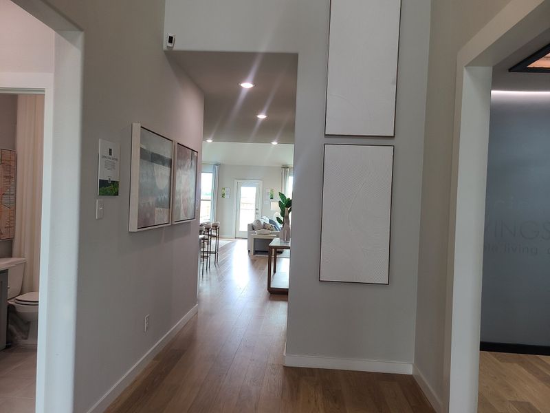 A bright hallway with modern art, wood flooring, and an open view to the living area.
