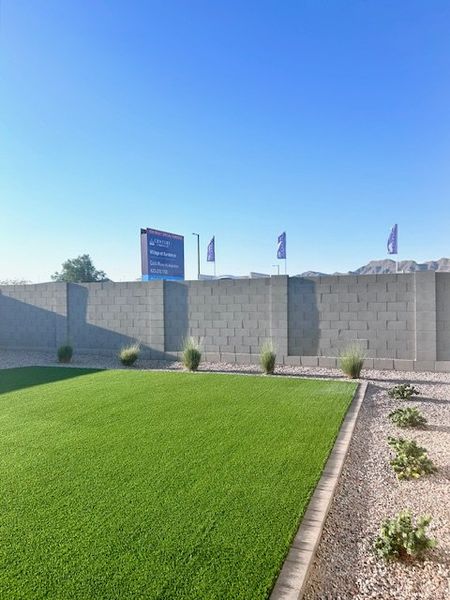 A landscaped yard with lush grass and a block fence in The Vistas Collection at Village at Sundance by Century Communities (Buckeye, AZ).