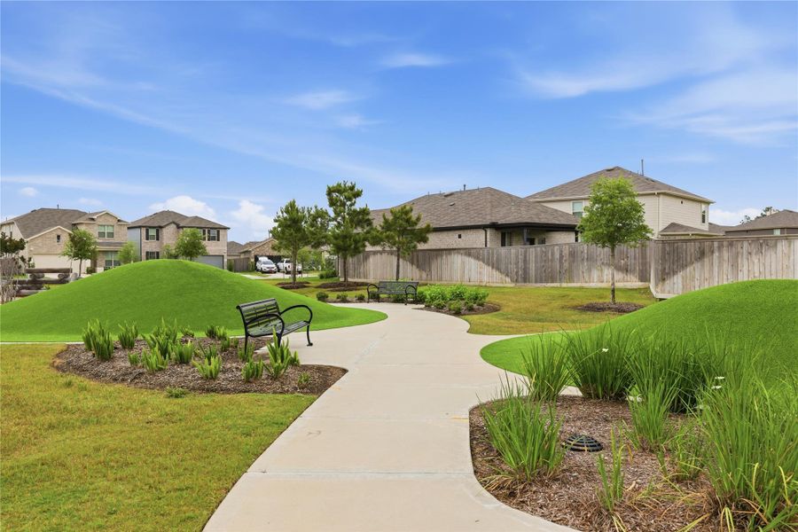 Charming neighborhood park view with a well-maintained walking path, landscaped greenery, and nearby homes. Ideal for outdoor relaxation and family-friendly living.