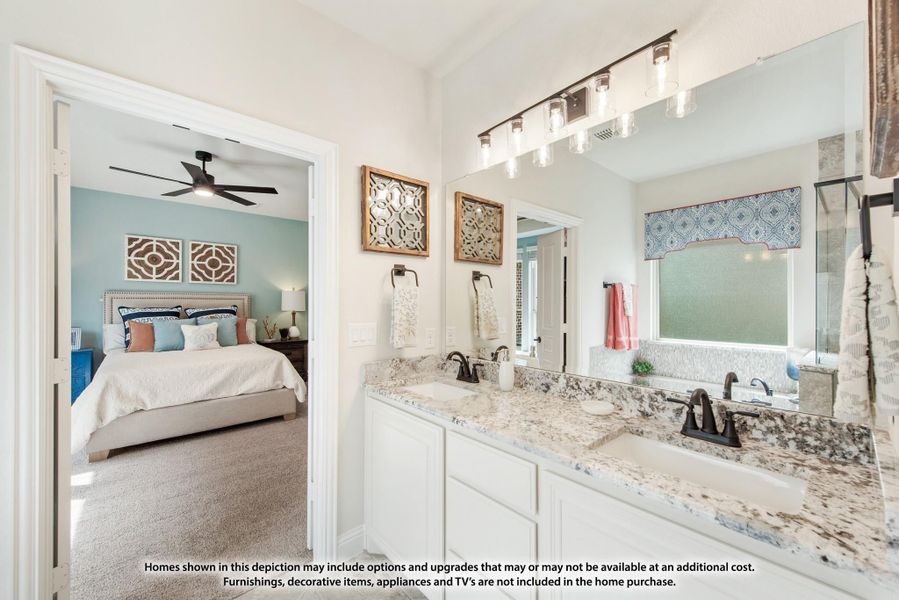 Ensuite bathroom with double vanity, granite countertops, and view into carpeted master bedroom with ceiling fan.