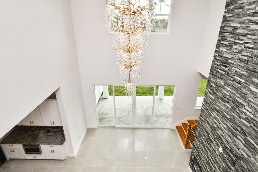 Experience dramatic vertical scale in the soaring two-story great room. A magnificent multi-tier crystal chandelier cascades from the ceiling, anchoring the space between the gourmet kitchen, stone-clad fireplace, and expansive sliding glass doors that lead to the rear patio.