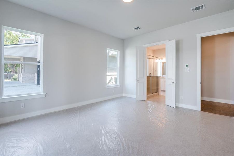 Unfurnished bedroom featuring wood-type flooring, ensuite bathroom, and multiple windows