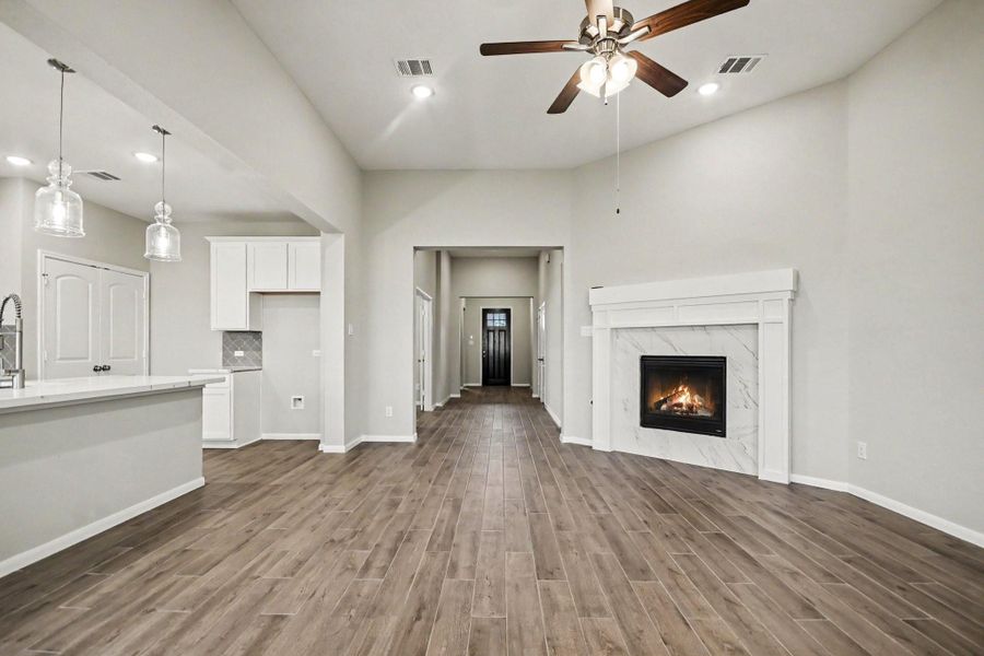 Open layout leading to a modern kitchen featuring sleek white cabinetry and stylish pendant lighting.