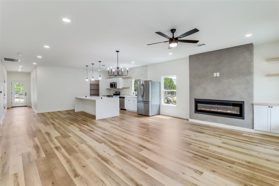 Unfurnished living room featuring light wood-style flooring, a large fireplace and recessed lighting