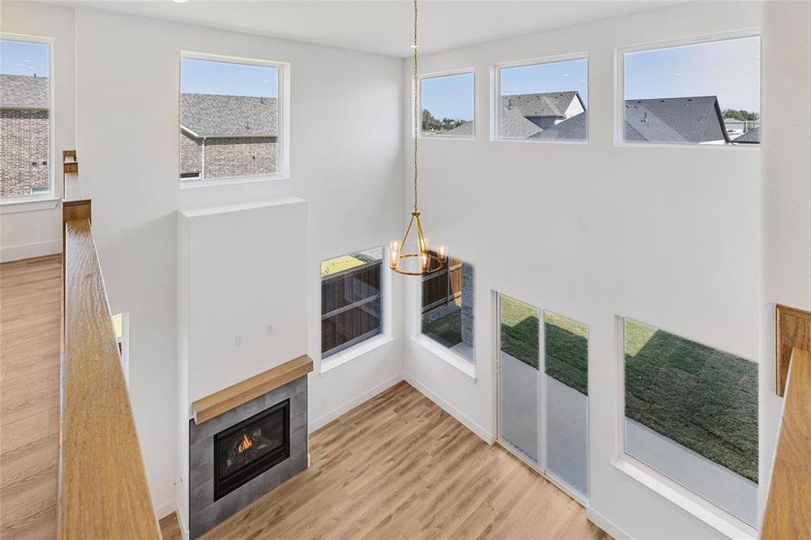 Living room featuring light hardwood / wood-style floors, a notable chandelier, a healthy amount of sunlight, and a tiled fireplace