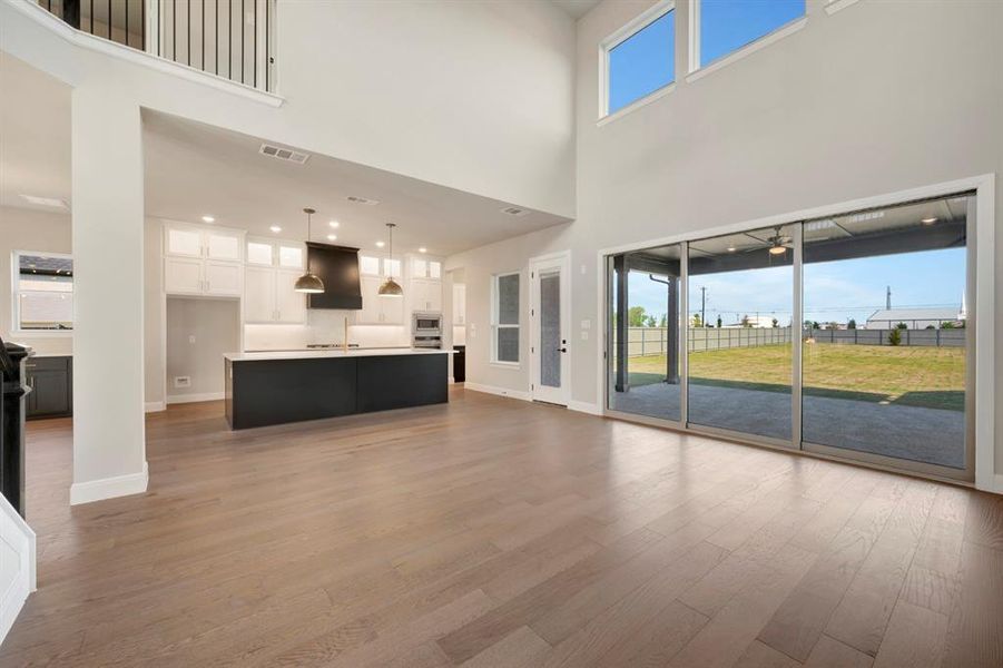Unfurnished living room featuring dark wood-style flooring, a high ceiling, and recessed lighting Unfurnished living room featuring dark wood-style flooring, a high ceiling, and recessed lighting