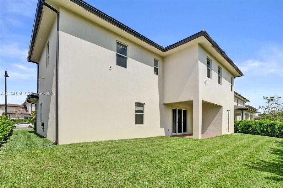 Two-story stucco exterior featuring multiple windows, a covered patio, and a sliding glass door