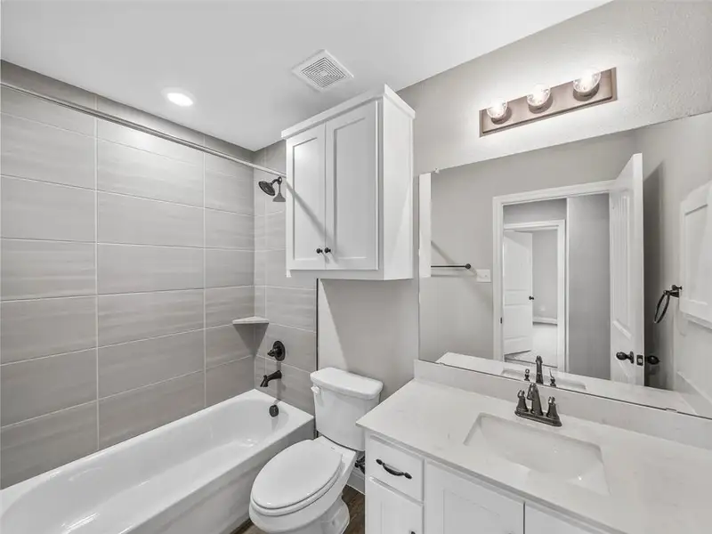 Bathroom featuring vanity, toilet, shower / washtub combination, and visible vents