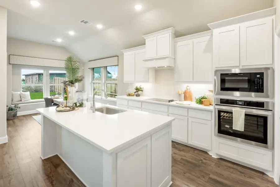 Kitchen with white cabinets, center island with sink, stainless steel appliances, and hardwood floors