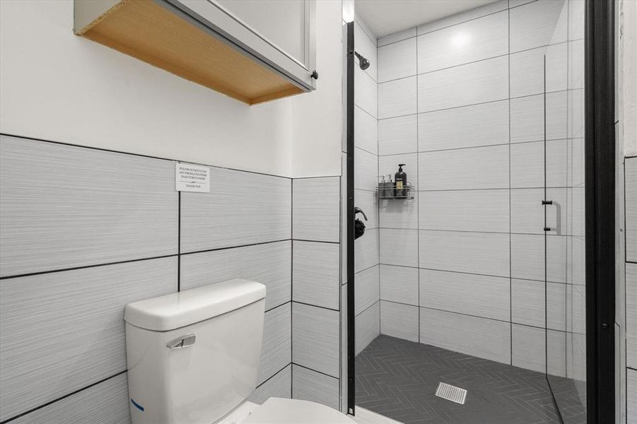 Full bathroom featuring a stall shower and tile walls Full bathroom featuring a stall shower and tile walls