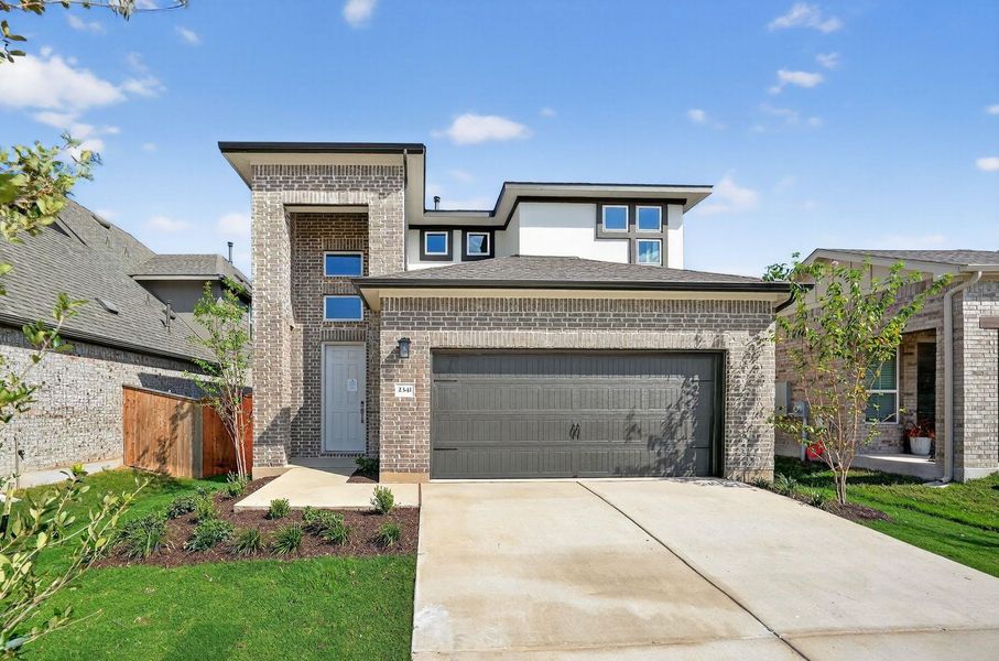 Prairie-style home with an attached garage, brick siding, and driveway Prairie-style home with an attached garage, brick siding, and driveway