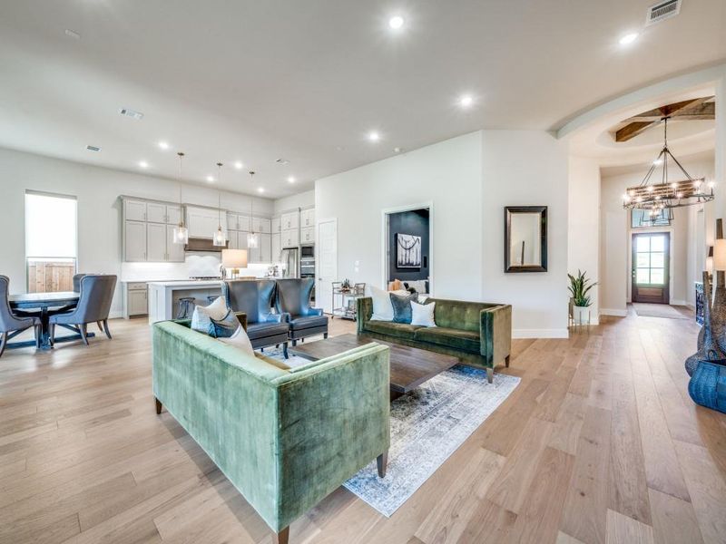 Living room with a chandelier, light wood-style flooring, recessed lighting, baseboards, and arched walkways