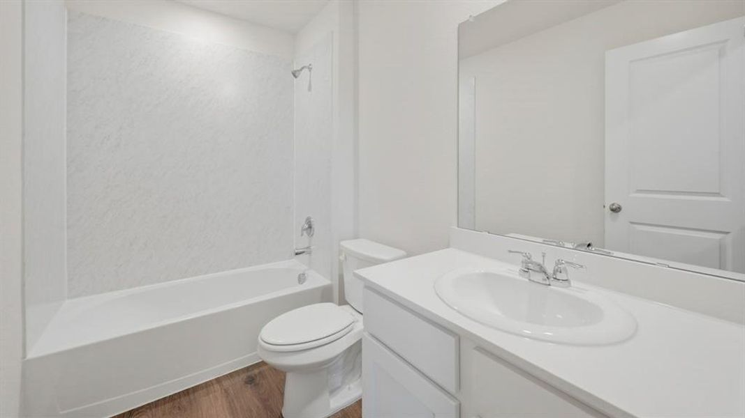 Full bath with vanity, dark wood finished floors, and bathing tub / shower combination Full bath with vanity, dark wood finished floors, and bathing tub / shower combination