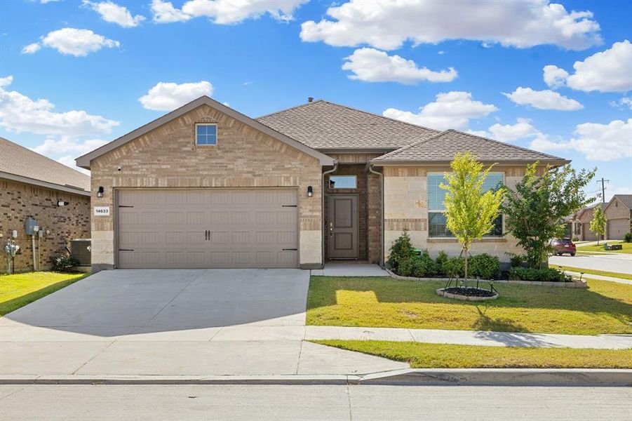 View of front facade featuring brick siding, a front lawn, driveway, an attached garage, and roof with shingles