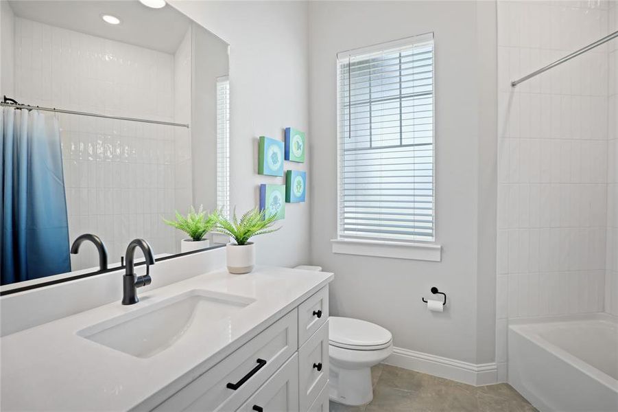 Full bathroom featuring toilet, vanity, baseboards, shower / bathtub combination with curtain, and tile patterned flooring Full bathroom featuring toilet, vanity, baseboards, shower / bathtub combination with curtain, and tile patterned flooring