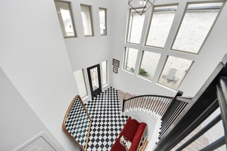 This photo showcases a spacious, bright entryway with high ceilings and large windows. The black-and-white checkered floor adds a classic touch, while a curved staircase leads to the upper level. The modern black front door complements the contemporary feel. This photo showcases a spacious, bright entryway with high ceilings and large windows. The black-and-white checkered floor adds a classic touch, while a curved staircase leads to the upper level. The modern black front door complements the contemporary feel.